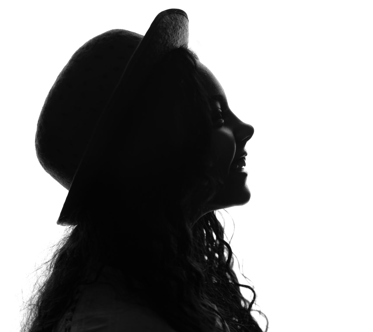 Artistic silhouette of a woman in profile wearing a hat, conveying elegance.